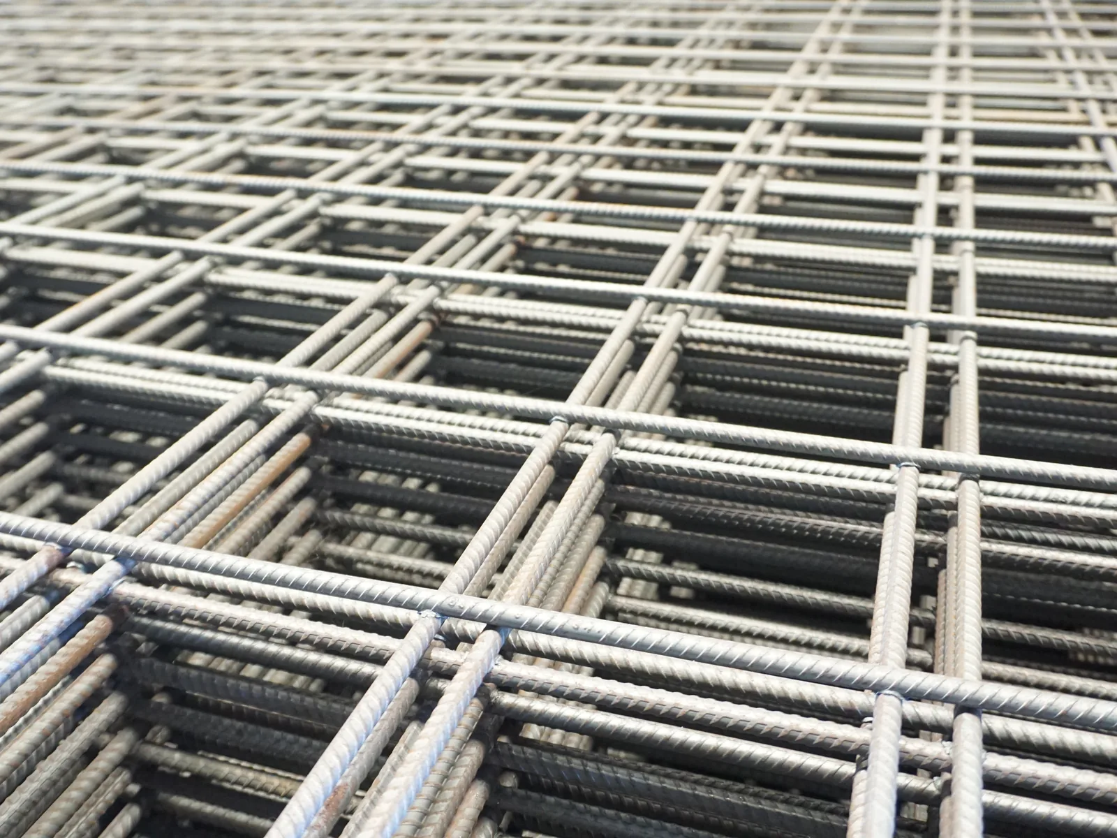 Lembaran wiremesh baja tersusun bertumpuk, memperlihatkan kisi persegi dan titik las di setiap persilangan kawat.